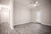 Located at 6767 Iron Bridge Rd in North Chesterfield, Virginia, this single-floor residence offers a thoughtfully designed layout with contemporary finishes throughout. Light wood-tone luxury vinyl plank flooring runs through the main living areas, complementing the neutral warm-gray walls and bright white trim that create a cohesive, modern aesthetic.

The open-concept living and dining area features crown molding, a ceiling fan with integrated lighting, and a decorative column accent that subtly defines the space. Natural light filters in through the windows, and the layout flows seamlessly into the kitchen. The kitchen is well-equipped with rich dark-brown cabinetry, light granite-style countertops, a stainless steel refrigerator, black range and microwave, a dishwasher, and a pendant-lit breakfast bar with sink.

The bedrooms are carpeted for comfort, each outfitted with ceiling fans and generous closet space, including walk-in closets with multi-tier shelving. One bedroom offers an exterior-facing window with neighborhood views. The bathrooms include a soaking tub with white subway tile surround, wood-toned vanity cabinetry, and light vinyl flooring that ties back to the main living areas, maintaining a consistent design throughout.