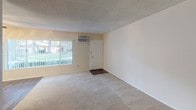 Located at 2550 E Ward Ter in Anaheim, California, this single-floor unit offers a functional and well-organized layout designed for comfortable everyday living. The living area greets visitors with a large window that frames views of lush greenery outside, filling the space with natural light. Soft carpeting underfoot and a textured ceiling contribute to a warm, relaxed ambiance, while a wall-mounted air conditioning unit ensures year-round comfort.

The galley-style kitchen is bright and efficiently designed, featuring crisp white cabinetry, gray countertops, a gas range, and a double sink. A skylight panel overhead floods the kitchen with additional light, and wood-look vinyl flooring runs throughout, providing a clean, cohesive aesthetic. A pass-through opening connects the kitchen to the adjacent dining and living area, which is anchored by a ceiling fan with integrated lighting.

The carpeted bedrooms offer a quiet retreat, with one room featuring sliding glass doors that open directly to a private outdoor patio area. The full bathroom is neatly appointed with a single-sink vanity topped with a gray countertop, white cabinetry, a combination tub and shower, and a jalousie window that allows for natural ventilation. Wood-look flooring ties the bathroom together with the rest of the unit's hard-surface areas.