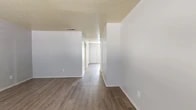 This two-story residence at 7200 Jewella Ave in Shreveport, Louisiana offers a practical and well-organized layout across two evenly divided floors. The main level features a welcoming entrance with wood-look plank flooring that flows throughout, leading into a bright living room illuminated by a large window with blinds. The galley-style kitchen is equipped with warm wood cabinetry lining both sides, light countertops, a white range, refrigerator, and a sink — offering ample storage and prep space. A half bathroom with a wall-mounted sink and hardwood-style flooring is also conveniently located on this floor. A staircase connects to the upper level, where both bedrooms are found. The generously sized primary bedroom features plush carpeting, a closet, a natural light-filled window, and a private en-suite bathroom. The second bedroom also features carpet flooring and benefits from natural light. A full bathroom with a tiled tub-shower combination serves the upper floor. Additional closet space is available on both levels. Textured ceilings are featured throughout, and a security system panel is visible near the entrance, adding a layer of convenience and comfort to this well-appointed multi-level home.