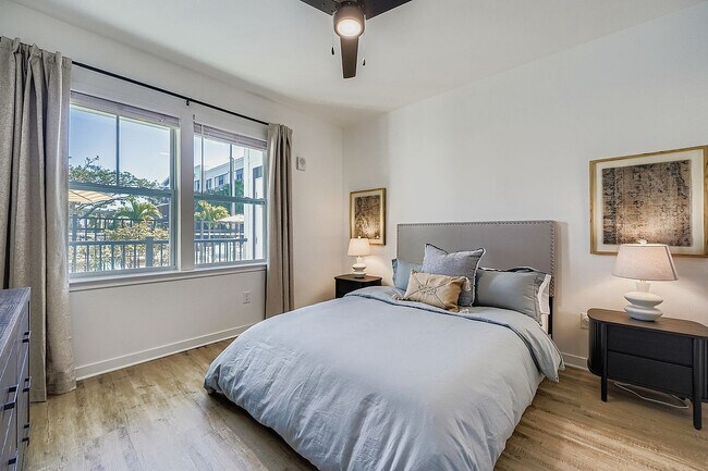 Acogedora habitación con decoración contemporánea, que cuenta con un gran ventanal con vistas a un exuberante paisaje exterior, una cama mullida con elegantes almohadas y una cálida iluminación ambiental. - Magnolia at Palm Bay