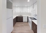 Located at 17350 NW 68th Ave in Hialeah, FL, this single-floor unit offers a clean, modern aesthetic throughout. The open-concept living and dining area is finished with light wood-style flooring and features a large floor-to-ceiling sliding glass door that floods the space with natural light and provides direct access to a balcony with outdoor views of surrounding greenery. A pendant light fixture adds a subtle decorative touch to the living space.

The kitchen is thoughtfully designed with a two-tone cabinetry scheme — dark wood lower cabinets paired with high-gloss white upper cabinets — complemented by light countertops and recessed lighting. White appliances, including a refrigerator, range, dishwasher, and microwave, are seamlessly integrated into the layout.

The bedrooms feature plush neutral carpeting and are generously proportioned, with one room offering access to a spacious walk-in closet fitted with wire shelving for organized storage. The bathroom is finished with large-format white tile flooring, a modern dark wood vanity, and a combined tub and shower enclosed by sleek sliding glass doors. Throughout, the unit maintains a bright, neutral palette that creates a clean and welcoming atmosphere.