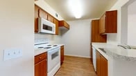 Located at 651 N Rose Dr in Placentia, CA, this well-appointed one-bedroom, one-bathroom residence offers an efficient and comfortable layout across a single floor. The open-concept living, dining, and kitchen area forms the heart of the home, where warm wood-tone laminate flooring flows throughout. The galley-style kitchen is lined with rich warm-toned wood cabinetry, granite-look countertops, and white appliances including a range, over-the-range microwave, and dishwasher. A peninsula with a sink connects the kitchen to the dining and living areas, enhancing the sense of openness. The living area is bright and airy, with a sliding glass door that opens onto a private balcony overlooking lush greenery — bringing in natural light and outdoor views. The spacious bedroom features soft carpeting, a ceiling fan with light fixture, and a window with natural light. Three closets throughout the unit provide generous storage options. The bathroom includes a wood-vanity with granite-look countertop, dual mirrors, and hardwood-style flooring. Clean neutral walls and consistent finishes throughout give this residence a cohesive, move-in-ready appeal.
