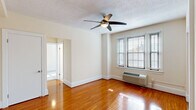 Situated in the desirable Cathedral Heights neighborhood of Washington, DC, this single-floor residence at 2301 Cathedral Ave NW offers a thoughtfully laid-out living space with a clean, neutral aesthetic throughout. The main living area is highlighted by warm hardwood flooring that catches natural light streaming through large, blind-fitted windows, creating a bright and welcoming atmosphere. A ceiling fan overhead adds both function and a finishing touch to the space. The kitchen is well-equipped with warm-toned wood cabinetry, dark granite-style countertops, a dishwasher, refrigerator, and a stainless steel sink, all accented by tile flooring and a window for natural ventilation. The bedroom features plush wall-to-wall carpeting, a ceiling fan, a closet, and a wide set of windows fitted with a wall-mounted HVAC unit for individual climate control. An additional carpeted room also benefits from a triple-pane window arrangement and its own HVAC unit, offering flexibility as a second bedroom or den. The bathroom presents a clean, all-white design with tile flooring, a shower-tub combo, and a frosted window for natural light and privacy. Throughout the residence, consistent finishes and an open flow contribute to a comfortable, functional living environment.