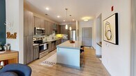 Located at 2841 Manorcrest Ct in Raleigh, NC, this one-bedroom, one-bathroom residence offers a thoughtfully designed open-concept layout across a single level. The kitchen is a standout feature, showcasing warm wood-toned cabinetry, granite countertops, a subway tile backsplash, and a full suite of stainless steel appliances. A central island with pendant lighting provides both prep space and casual seating, flowing seamlessly into the living room. The living area is characterized by light wood-style flooring, a bold teal accent wall, a ceiling fan, and large windows that invite natural light and treetop views. A glass door opens to a private balcony overlooking a lush, tree-lined outdoor setting. The bedroom is a comfortable retreat featuring a ceiling fan, large windows with outdoor greenery views, and soft carpeting. The full bathroom is finished with large-format tile flooring, a granite vanity with wood-toned cabinetry, and a full soaking tub. A dedicated closet provides practical storage. The overall design balances contemporary finishes with warm, inviting tones, creating a well-appointed and functional living space in a desirable Raleigh location.