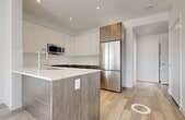 Located at 11805 30 Avenue SW in Edmonton, Alberta, this thoughtfully designed 2-bedroom, 2-bathroom unit offers a clean, modern aesthetic across a single floor. Light oak-toned hardwood flooring flows throughout the main living areas and bedrooms, complemented by crisp white walls that enhance the sense of brightness and space.

The kitchen is a standout feature, boasting two-tone cabinetry with white upper cabinets and wood-grain lower cabinets, a quartz-topped island with an undermount sink, and a full suite of stainless steel appliances including a refrigerator, stove, and built-in microwave. The layout promotes easy movement and functional workflow.

Both bedrooms are well-proportioned and filled with natural light from large windows offering open views. Each room features dedicated closet space with built-in shelving. The primary bedroom is notably spacious and is positioned adjacent to one of the two full bathrooms.

Both bathrooms maintain the modern palette, featuring white marble-look tile flooring, wood-toned vanity cabinetry with quartz countertops, chrome fixtures, and full soaker tub-shower combinations. A central hallway connects all rooms efficiently, contributing to a logical and livable floor plan. The overall ambiance is clean, contemporary, and move-in ready.