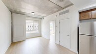 Located at 1901 Callowhill St in Philadelphia's vibrant Callowhill neighborhood, this one-bedroom, two-bathroom unit offers a well-designed single-floor layout with an industrial-modern aesthetic. Exposed concrete ceilings contrast beautifully with light hardwood flooring that flows throughout the main living areas, creating a contemporary urban feel.

The open-concept kitchen is a standout feature, equipped with warm-toned wood cabinetry, stainless steel appliances including a refrigerator, range, and microwave, and a generous island with a white quartz countertop and pendant lighting overhead — ideal for both cooking and casual dining. The kitchen opens seamlessly into the living area, which benefits from an airy, loft-like atmosphere thanks to the exposed concrete ceiling and natural light streaming in from large windows.

The bedroom is a comfortable, well-proportioned space with light hardwood floors, white walls, and a large window offering views of the surrounding Philadelphia streetscape. A stacked in-unit washer and dryer adds convenience. Both bathrooms are finished with light tile flooring and marble-style tiled tub and shower surrounds, paired with clean white fixtures and vanities, giving them a crisp, modern look. The overall ambiance of this unit is clean, contemporary, and functional.