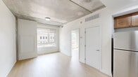 Located at 1901 Callowhill St in Philadelphia's vibrant Callowhill neighborhood, this one-bedroom, two-bathroom unit offers a well-designed single-floor layout with an industrial-modern aesthetic. Exposed concrete ceilings contrast beautifully with light hardwood flooring that flows throughout the main living areas, creating a contemporary urban feel.

The open-concept kitchen is a standout feature, equipped with warm-toned wood cabinetry, stainless steel appliances including a refrigerator, range, and microwave, and a generous island with a white quartz countertop and pendant lighting overhead — ideal for both cooking and casual dining. The kitchen opens seamlessly into the living area, which benefits from an airy, loft-like atmosphere thanks to the exposed concrete ceiling and natural light streaming in from large windows.

The bedroom is a comfortable, well-proportioned space with light hardwood floors, white walls, and a large window offering views of the surrounding Philadelphia streetscape. A stacked in-unit washer and dryer adds convenience. Both bathrooms are finished with light tile flooring and marble-style tiled tub and shower surrounds, paired with clean white fixtures and vanities, giving them a crisp, modern look. The overall ambiance of this unit is clean, contemporary, and functional.