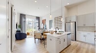 Located at 8000 Crescent Cir in Randolph, NJ, this well-appointed 2-bedroom, 2-bathroom residence offers a thoughtfully designed single-floor layout. The open-concept living, dining, and kitchen area serves as the heart of the home, bathed in natural light from floor-to-ceiling sliding glass doors that lead directly to a private patio with outdoor views. The kitchen is outfitted with white shaker cabinetry, quartz countertops, a central island with an undermount sink, stainless steel appliances including a refrigerator, range, and built-in microwave, plus a classic subway tile backsplash and pendant lighting. The living area features light hardwood-style flooring and a decorative wine rack wall display. The spacious primary bedroom offers high ceilings, generous closet space, and an en-suite bathroom with a glass-enclosed walk-in shower with wood-look tile surround. The second bedroom is equally comfortable, accompanied by a full bathroom featuring a soaking tub and shower combination. Four closets provide abundant storage throughout, while a dedicated laundry area and utility room add everyday convenience. Recessed lighting and a clean, neutral palette create a bright, cohesive ambiance throughout.