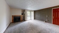 Located at 1890 Beechwood Ave NE in North Canton, Ohio, this one-bedroom, one-bathroom unit offers a practical and well-organized single-floor layout. The combined kitchen and living area serves as the heart of the unit, where the living room features plush carpeting, a textured ceiling, a wood-burning fireplace with a wood-trimmed surround, and a distinctive tile accent wall. A sliding glass door floods the space with natural light and provides access to a private outdoor patio. The kitchen is efficiently designed with light wood-style flooring, gray cabinetry, light laminate countertops, a double-basin stainless steel sink, and white appliances including a range, refrigerator, and dishwasher. A ceiling fan with lighting is centrally positioned above the kitchen area. The bedroom is a comfortable, well-proportioned room with wall-to-wall carpet, a ceiling fan, a textured ceiling, and a window that allows for natural light. A dedicated closet provides ample storage. The full bathroom includes tile flooring, a tub/shower combination, a toilet, and a vanity with a granite-style countertop. A hallway connects the main living areas to the private spaces, completing this functional and cozy floor plan.
