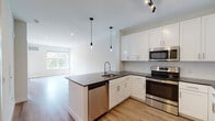 Located at 10 Willard Rd in Norwalk, Connecticut, this thoughtfully designed single-floor residence offers a clean, contemporary aesthetic throughout. The open-concept layout connects the kitchen and living area seamlessly, creating a bright and functional living space bathed in natural light from large windows with views of surrounding greenery.

The kitchen is a standout feature, showcasing crisp white shaker cabinetry that extends to the ceiling for ample storage, dark quartz countertops, and a full suite of stainless steel appliances including a range, built-in microwave, refrigerator, and dishwasher. A central island with an integrated sink and stylish pendant lighting serves as both a prep area and a casual gathering spot. White subway tile backsplash adds a classic touch to the modern design.

Light hardwood flooring runs throughout the unit, complementing the neutral color palette and recessed lighting that keep the space feeling airy and open. The bedroom area offers a generous footprint with natural light and convenient access to in-unit stacked laundry. The bathroom features a dark quartz vanity countertop, an undermount sink, white cabinetry, and a full-width mirror. Every detail of this residence reflects a commitment to modern comfort and functional design.