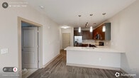 Located at 2610 Erwin Rd in Durham, NC, this well-appointed single-floor unit offers a thoughtfully designed layout that maximizes every square foot. The open-concept kitchen serves as the centerpiece of the space, featuring rich wood-toned cabinetry, a white quartz peninsula with an undermount sink, subway tile backsplash, and a full suite of stainless steel appliances including a refrigerator with ice maker, electric range, built-in microwave, and dishwasher. Stylish pendant lighting and adjustable track lighting illuminate the kitchen and flow seamlessly into the adjacent living area, which is finished with wood-look plank flooring throughout. The bedroom offers plush carpeting, a ceiling fan, a generous closet, and a window with views to the outdoors, filling the room with natural light. The full bathroom is clean and modern, featuring a tiled tub-and-shower combination with a sliding glass door, wood-toned vanity with quartz countertop, and wood-look flooring. Additional highlights include a dedicated laundry area, utility and storage closets, and a hallway connecting all areas of the unit for a practical, efficient flow throughout.