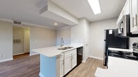 Located at 300 North Royal Oaks Boulevard in Franklin, TN, this one-bedroom, one-bathroom unit offers a well-designed single-level layout with a clean, modern aesthetic throughout. Wood-look flooring flows seamlessly across all living areas, complemented by neutral gray walls and bright white trim that create a light, cohesive atmosphere.

The open-concept kitchen and living area is the heart of the home. The kitchen features a spacious peninsula with a white quartz countertop and integrated sink, white shaker-style cabinetry, a classic subway tile backsplash, and a full suite of stainless steel appliances including a range, microwave, and refrigerator. The adjoining living room is anchored by a white brick wood-burning fireplace and benefits from a ceiling fan overhead. A sliding glass door opens to a private balcony, offering pleasant outdoor views and natural light.

The bedroom is a comfortable, well-proportioned retreat with a ceiling fan, a window with blinds, and access to a hallway with a closet. Crown molding adds a refined touch to the living and bedroom areas. The bathroom is clean and functional, featuring a white vanity with quartz countertop, a tiled tub-shower combination, and wood-look flooring. A dedicated hallway provides additional storage and smooth connectivity between all rooms.