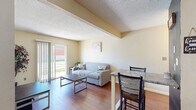 This single-floor unit in Montgomery, Indiana, offers a straightforward and functional layout designed for comfortable everyday living. The living area serves as the central gathering space, featuring warm hardwood-style flooring, neutral beige walls, and a textured ceiling. A sliding glass door floods the room with natural light and provides views of the outdoors, while an adjacent bar-height dining area offers a convenient spot for casual meals.

The kitchen is well-equipped with white cabinetry providing ample storage, granite-style countertops, and black appliances including a full-size refrigerator, electric range with overhead ventilation, and microwave. The warm-toned accent walls add a distinctive character to the space, complementing the hardwood-style flooring that continues from the living area.

Multiple bedrooms are carpeted and finished in soft neutral tones, each offering a calm and restful atmosphere. Natural light filters in through window blinds, and at least one bedroom includes a dedicated closet with built-in shelving for organized storage.

The bathroom features tile flooring, a wall-mounted storage cabinet, and clean, accessible fixtures in a bright, neutral setting. Overall, the unit presents a practical and cohesive living environment with consistent finishes throughout.