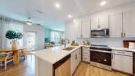 Located at 4502 W McCoy St in Tampa's 33616 zip code, this single-floor residence offers a well-designed, open-concept layout with modern finishes and a bright, cheerful aesthetic throughout. The kitchen is equipped with stainless steel appliances, including a French door refrigerator, range, and over-the-range microwave, complemented by two-tone light wood cabinetry, white quartz countertops, a subway tile backsplash, and a peninsula with an undermount sink — all flowing seamlessly into the living and dining areas. A dedicated dining nook features a glass door that invites natural light and provides outdoor access. The living room is a standout space, highlighted by soft teal accent walls, large windows with sheer curtains, and warm wood-look flooring that runs throughout the unit. The primary bedroom features a ceiling fan, teal accent wall, and en-suite bathroom with a glass-enclosed walk-in shower and wood vanity. A second well-proportioned bedroom mirrors the same warm palette and ceiling fan detail. The second bathroom offers a full soaking tub/shower combo, extended vanity with white countertops, and wood-look flooring. The overall ambiance is modern, airy, and cohesive, with consistent finishes creating a polished living environment.