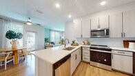 Located at 4502 W McCoy St in Tampa's 33616 zip code, this single-floor residence offers a well-designed, open-concept layout with modern finishes and a bright, cheerful aesthetic throughout. The kitchen is equipped with stainless steel appliances, including a French door refrigerator, range, and over-the-range microwave, complemented by two-tone light wood cabinetry, white quartz countertops, a subway tile backsplash, and a peninsula with an undermount sink — all flowing seamlessly into the living and dining areas. A dedicated dining nook features a glass door that invites natural light and provides outdoor access. The living room is a standout space, highlighted by soft teal accent walls, large windows with sheer curtains, and warm wood-look flooring that runs throughout the unit. The primary bedroom features a ceiling fan, teal accent wall, and en-suite bathroom with a glass-enclosed walk-in shower and wood vanity. A second well-proportioned bedroom mirrors the same warm palette and ceiling fan detail. The second bathroom offers a full soaking tub/shower combo, extended vanity with white countertops, and wood-look flooring. The overall ambiance is modern, airy, and cohesive, with consistent finishes creating a polished living environment.