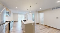 Located at 2305 Sokol Ct in Darien, IL, this thoughtfully designed one-bedroom, one-bathroom residence offers a clean, contemporary aesthetic with high-quality finishes throughout. The open-concept kitchen and living area serves as the heart of the home, anchored by a curved quartz-topped island with an undermount sink and stylish globe pendant lighting overhead. The kitchen is equipped with warm wood cabinetry, a white subway tile backsplash, and a full suite of stainless steel appliances, including a refrigerator, electric range, and microwave. Light wood-tone luxury vinyl plank flooring flows seamlessly throughout the entire unit, enhancing the bright, airy atmosphere. The living area benefits from large sliding glass door access and vertical blinds, allowing for generous natural light. The bedroom is a comfortable, well-proportioned retreat featuring a ceiling fan, a double-door closet, and a window with outdoor views. The full bathroom is finished with striking marble-look tile on both the floor and tub surround, paired with a wood-tone vanity for a refined contrast. A dedicated in-unit laundry room houses a full-size washer and dryer, adding everyday convenience to this well-appointed home.