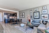Located in the heart of Midtown Atlanta, this high-rise residence at 890 Juniper St NE offers a sophisticated urban living experience defined by sweeping panoramic views of the Atlanta skyline. The single-floor layout is thoughtfully designed to maximize both style and functionality throughout.

The living area is a standout feature, anchored by dramatic floor-to-ceiling corner windows that flood the space with natural light and frame unobstructed views of the city below. Light wood flooring runs throughout, complementing the warm, contemporary aesthetic.

The kitchen is outfitted with rich dark espresso cabinetry extending to the ceiling for ample storage, granite countertops, a mosaic tile backsplash, and a full suite of stainless steel appliances including a side-by-side refrigerator and gas range.

The bedroom continues the floor-to-ceiling window motif, offering breathtaking skyline views as a backdrop. It connects seamlessly to a spa-inspired ensuite bathroom featuring marble-look tile flooring, a glass-enclosed walk-in shower, a double vanity with granite countertops, and navy blue cabinetry with modern fixtures.

Additional conveniences include an in-unit washer with built-in shelving and storage, rounding out this well-appointed Midtown Atlanta residence.