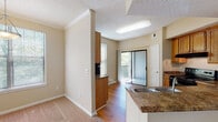 Located at 4390 Clearwater Way in Lexington, Kentucky, this single-floor residence offers a well-organized layout with a range of practical and comfortable features throughout. The living area is a bright, open space highlighted by a tile-surround fireplace, crown molding, a ceiling fan, and multiple windows that allow generous natural light to fill the room. A sliding glass door leads directly to a balcony, extending the living space outdoors. Adjacent to the living area, a dedicated dining nook is illuminated by a pendant light fixture and surrounded by windows with outdoor views. The kitchen is equipped with warm oak cabinetry, granite-style countertops, a double-basin sink, and black appliances including an electric range. A partial peninsula separates the kitchen from the living and dining areas, creating a functional open-concept flow. Hardwood flooring runs through the kitchen and dining areas, while plush carpet covers the bedrooms. Each bedroom includes a ceiling fan, natural light from windows, and access to closet space. The bathrooms feature warm wood vanities with granite-style countertops, tiled tub-shower combinations, and hardwood flooring, offering a clean and cohesive aesthetic. Crown molding and textured ceilings are consistent design elements found throughout the home.