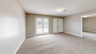 Located at 7101 Tulane Rd N in Horn Lake, Mississippi, this single-story, one-bedroom, one-bathroom home offers a practical and comfortable layout across a well-utilized floor plan. The living room is a bright, open space featuring plush carpet, neutral beige walls, and a set of French doors that invite natural light and provide outdoor access. A second window further enhances the room's airy feel. An elegant chandelier anchors the dining area, which flows seamlessly into the galley-style kitchen. The kitchen features warm wood-trimmed cabinetry with white doors, white appliances including an electric range and refrigerator, a stainless steel sink, and rich hardwood flooring that adds warmth to the space. The spacious bedroom is carpeted and well-lit by a large window with outdoor views, offering a serene retreat. A hallway leads to the bathroom, which includes a wide vanity with wood-trimmed cabinetry, a large mirror, and a lighted fixture above. The walk-in closet provides generous storage with dual wire shelving rods lining the walls. A dedicated utility room adds further functional convenience. Textured ceilings are consistent throughout, complementing the home's clean, neutral color palette.