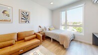 Located at 355 Glendale Blvd in the vibrant Echo Park neighborhood of Los Angeles, this thoughtfully designed one-bedroom, one-bathroom unit makes excellent use of its compact footprint across a single floor. The open layout connects the main living area to a well-appointed kitchen, which serves as a visual highlight with its striking deep-blue subway tile backsplash, sleek quartz countertops, matte black fixtures, stainless steel undermount sink, and integrated dishwasher. White upper cabinetry and light wood lower cabinets complete the modern aesthetic. The bedroom is a bright, comfortable retreat featuring light hardwood-style flooring, crisp white walls, and a large picture window that floods the space with natural light and offers open city views. The bathroom is clean and contemporary, finished with large-format white floor tiles, a floating vanity with an oversized mirror, white subway tile in the shower, and a curtained tub-shower combination. A standout practical feature is the in-unit stacked washer and dryer, neatly tucked into a dedicated closet alcove off the main living area. Light wood flooring flows throughout, tying the space together with warmth and cohesion.