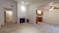Located at 7727 South Yale Avenue in Tulsa, Oklahoma, this single-floor residence offers a well-organized layout designed for comfortable everyday living. The living room serves as the heart of the home, highlighted by a tile-surround wood-burning fireplace set against a crisp white wall, with plush carpeting throughout and track lighting overhead. An open archway connects the living area to the galley-style kitchen, which features warm wood cabinetry lining both walls, dark stone-look countertops, a stainless sink, and light hardwood flooring — providing ample storage and prep space in an efficient corridor layout. A ceiling fan with light kit is positioned near the kitchen passthrough, enhancing airflow throughout the common areas. The bedrooms are generously sized, each finished with soft carpeting, ceiling fans, and sliding glass doors fitted with vertical blinds that invite natural light and provide outdoor access. The primary bathroom includes a dedicated vanity area with a wood cabinet, large mirror, and well-lit fixture, while the additional full bathrooms feature tub/shower combinations with tile surrounds and vinyl flooring. The textured ceilings throughout and neutral color palette create a cohesive, move-in-ready atmosphere across the entire space.