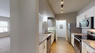 Located on Libby Road in Plano, Texas, this single-story residence offers a well-organized layout designed for comfortable everyday living. The galley-style kitchen is appointed with white shaker cabinetry, granite-look countertops, stainless steel appliances including a refrigerator and dishwasher, and wood-look flooring underfoot. Track lighting overhead provides focused illumination throughout the cooking space.

The living area is a generously proportioned room featuring plush carpet, neutral warm-toned walls, and a wood-mantled fireplace clad in stone tile that serves as a natural focal point. Natural light filters in through blinds-fitted windows, enhancing the open ambiance of the space.

The bedrooms are carpeted and each equipped with ceiling fans, offering a comfortable and functional retreat. Windows provide exterior views and additional natural light. One bedroom connects directly to a well-appointed bathroom featuring a dual-sink vanity with granite-look countertops, wood-look flooring, and access to a spacious walk-in closet with built-in shelving and hanging rods.

A secondary bathroom includes a soaking tub and shower combination with decorative tile accenting, complementing the overall clean, neutral aesthetic carried throughout the home.