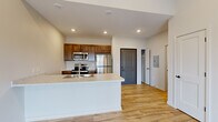 Located at 1220 W Highland Blvd in Lincoln, Nebraska, this thoughtfully designed one-bedroom, one-bathroom unit offers a compact yet functional living experience across a single floor. The open-concept layout connects the kitchen and living area seamlessly, creating a sense of spaciousness throughout. Light-toned hardwood-style flooring runs continuously through the space, complementing the crisp white walls and recessed lighting above.

The kitchen is a standout feature, anchored by a peninsula with a light stone-look countertop, an integrated sink, and dark walnut-toned cabinetry. A full suite of stainless steel appliances — including a refrigerator, electric range, microwave, and dishwasher — adds a modern, polished finish. The living area benefits from vaulted ceilings and a sliding glass door that opens to a private balcony, allowing natural light to pour in and offering open outdoor views.

The bedroom is a well-proportioned, quiet retreat with large windows, a wall-unit HVAC system, and continued hardwood-style flooring. A dedicated closet provides practical storage. The bathroom features a full tub-shower combination with chrome fixtures and a clean, minimalist design. The overall ambiance is fresh, modern, and move-in ready, ideal for those seeking a well-appointed home in Lincoln.