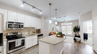 Located in Brookhaven, GA, this thoughtfully designed one-bedroom, one-bathroom residence offers a well-appointed layout across a single floor. The open-concept kitchen is a standout feature, showcasing crisp white shaker cabinetry, granite countertops, a central island with pendant lighting, stainless steel appliances, and a tile backsplash — all illuminated by sleek track lighting. Hardwood-style flooring flows throughout the main living areas, seamlessly connecting the kitchen to the living room.

The living room is bright and inviting, anchored by French doors topped with a transom window that ushers in abundant natural light and provides outdoor views. A ceiling fan adds to the comfort of the space.

The bedroom offers a cozy retreat with plush carpeting, a bold accent wall, a woven pendant light fixture, and windows overlooking the outdoors. A dedicated closet provides convenient storage directly off the bedroom.

The bathroom features a white vanity with a light stone countertop and a shower-tub combination. Neutral gray tones throughout the home create a calm, cohesive ambiance, making this Brookhaven residence both functional and stylish.