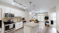Located in Brookhaven, GA, this thoughtfully designed one-bedroom, one-bathroom residence offers a well-appointed layout across a single floor. The open-concept kitchen is a standout feature, showcasing crisp white shaker cabinetry, granite countertops, a central island with pendant lighting, stainless steel appliances, and a tile backsplash — all illuminated by sleek track lighting. Hardwood-style flooring flows throughout the main living areas, seamlessly connecting the kitchen to the living room.

The living room is bright and inviting, anchored by French doors topped with a transom window that ushers in abundant natural light and provides outdoor views. A ceiling fan adds to the comfort of the space.

The bedroom offers a cozy retreat with plush carpeting, a bold accent wall, a woven pendant light fixture, and windows overlooking the outdoors. A dedicated closet provides convenient storage directly off the bedroom.

The bathroom features a white vanity with a light stone countertop and a shower-tub combination. Neutral gray tones throughout the home create a calm, cohesive ambiance, making this Brookhaven residence both functional and stylish.