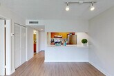 Located at 15690 Bull Run Rd in Miami Lakes, FL, this one-bedroom, one-bathroom residence offers a well-organized single-floor layout designed for comfortable everyday living. Light wood-look flooring runs throughout the main living areas, complementing the neutral, bright color palette and textured ceilings. The open-concept combined living and dining room is anchored by a full-height sliding glass door that invites abundant natural light and provides direct access to a private balcony overlooking lush greenery. A pass-through kitchen counter connects the living area to the galley-style kitchen, which features warm wood cabinetry, white countertops, stainless steel appliances including a refrigerator, electric range, and dishwasher, as well as track lighting overhead. The hallway leads to three closets, offering generous storage throughout. The bedroom is carpeted for comfort, with a window fitted with blinds providing soft natural light. The full bathroom includes a tiled shower-tub combination finished in clean white. The space is thoughtfully laid out to maximize functionality, with a practical flow from the entryway through to the living areas and private quarters.