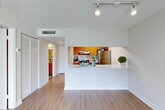 Located at 15690 Bull Run Rd in Miami Lakes, FL, this one-bedroom, one-bathroom residence offers a well-organized single-floor layout designed for comfortable everyday living. Light wood-look flooring runs throughout the main living areas, complementing the neutral, bright color palette and textured ceilings. The open-concept combined living and dining room is anchored by a full-height sliding glass door that invites abundant natural light and provides direct access to a private balcony overlooking lush greenery. A pass-through kitchen counter connects the living area to the galley-style kitchen, which features warm wood cabinetry, white countertops, stainless steel appliances including a refrigerator, electric range, and dishwasher, as well as track lighting overhead. The hallway leads to three closets, offering generous storage throughout. The bedroom is carpeted for comfort, with a window fitted with blinds providing soft natural light. The full bathroom includes a tiled shower-tub combination finished in clean white. The space is thoughtfully laid out to maximize functionality, with a practical flow from the entryway through to the living areas and private quarters.