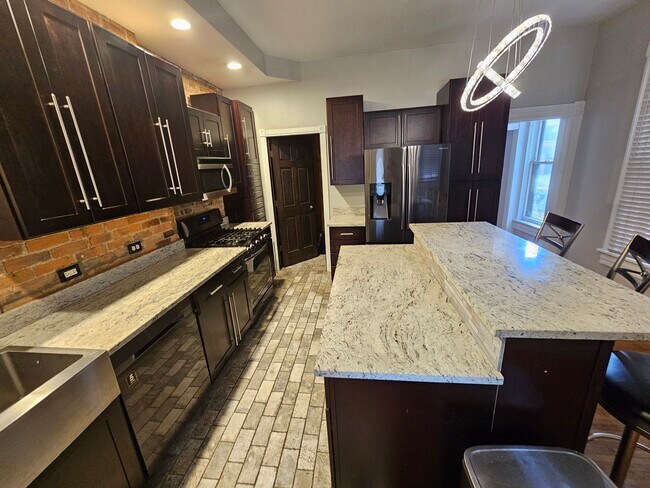 Algunos ladrillos a la vista, electrodomésticos modernos de acero inoxidable y azulejos tipo ladrillo neoyorquino. - 943 Highland St