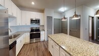 Located in Cornelius, NC, this single-floor residence offers a thoughtfully designed layout with modern finishes throughout. The kitchen serves as a standout feature, showcasing crisp white shaker cabinetry, a classic subway tile backsplash, granite countertops, and a generously sized island illuminated by stylish brushed nickel pendant lights. Stainless steel appliances, including a refrigerator with ice maker, electric range, microwave, and dishwasher, complete the space. Wood-look flooring runs through the kitchen and connecting areas, adding warmth and durability. The bedrooms are comfortable and well-lit, each featuring plush carpeting, neutral-toned walls, ceiling fans with light fixtures, and windows fitted with blinds that allow for natural light while maintaining privacy. The bathroom mirrors the home's cohesive design aesthetic, featuring a white vanity with granite countertop, wood-look flooring, a framed mirror, and a full tub-shower combination. Gray-toned interior doors and brushed nickel hardware provide a consistent, contemporary feel throughout the home. The overall ambiance is clean, modern, and move-in ready, making this Cornelius residence a practical and attractive living space.