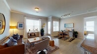 This single-floor residence offers a thoughtfully designed layout that balances comfort and functionality throughout. The open-concept living and dining area is bathed in natural light from multiple large windows dressed with blinds and sheer curtains, highlighting the light wood-style flooring and crown molding that run throughout the space. The living room features a warm, contemporary aesthetic, with a leather sofa, swivel accent chair, and a textured coffee table anchored by a plush area rug. Adjacent to it, the dining area accommodates a round wooden table and chairs beneath track lighting, with a sideboard and artwork completing the space. The kitchen is well-equipped with dark espresso cabinetry, granite countertops, stainless steel appliances including a refrigerator, range, and microwave, along with a peninsula with a double sink and pendant lighting overhead. The primary bedroom is a serene retreat with crown molding, direct access to a private balcony offering open exterior views, and ample room for a full furniture suite. Additional bedrooms are spacious and finished with the same light flooring and neutral tones. Both bathrooms feature granite vanities, dark cabinetry, and tiled soaking tub-shower combinations, offering a clean and polished finish throughout.