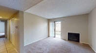 This single-floor residence offers a well-organized layout with comfortable living spaces throughout. The living room serves as the centerpiece of the home, featuring plush wall-to-wall carpeting, a classic fireplace, and a sliding glass door fitted with vertical blinds that opens to the outdoors, allowing natural light to fill the room. A textured ceiling adds dimension to the space.

The kitchen is designed for efficiency, featuring warm oak cabinetry, light-toned countertops, and tile flooring. A pass-through window connects the kitchen to an adjacent dining or flex area, promoting an open, connected feel. The kitchen is equipped with a range and refrigerator, with ample cabinet and counter storage on both sides of the galley-style layout.

The bedrooms are carpeted and each includes a closet with wood-tone sliding doors and a window that brings in natural light, creating bright and functional personal spaces. One bedroom features direct access to a full bathroom, providing added convenience.

The bathroom is appointed with tile flooring, a full soaking tub and shower combination, a toilet, and a vanity topped with granite-style countertops framed by wood cabinetry. Throughout the home, neutral wall tones and consistent finishes create a cohesive and inviting atmosphere.