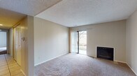 This single-floor residence offers a well-organized layout with comfortable living spaces throughout. The living room serves as the centerpiece of the home, featuring plush wall-to-wall carpeting, a classic fireplace, and a sliding glass door fitted with vertical blinds that opens to the outdoors, allowing natural light to fill the room. A textured ceiling adds dimension to the space.

The kitchen is designed for efficiency, featuring warm oak cabinetry, light-toned countertops, and tile flooring. A pass-through window connects the kitchen to an adjacent dining or flex area, promoting an open, connected feel. The kitchen is equipped with a range and refrigerator, with ample cabinet and counter storage on both sides of the galley-style layout.

The bedrooms are carpeted and each includes a closet with wood-tone sliding doors and a window that brings in natural light, creating bright and functional personal spaces. One bedroom features direct access to a full bathroom, providing added convenience.

The bathroom is appointed with tile flooring, a full soaking tub and shower combination, a toilet, and a vanity topped with granite-style countertops framed by wood cabinetry. Throughout the home, neutral wall tones and consistent finishes create a cohesive and inviting atmosphere.