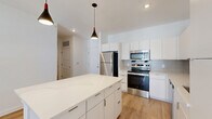 Located at 301 Ben Allen Rd in Nashville, TN, this well-designed one-bedroom, one-bathroom residence offers a clean, modern aesthetic across a comfortable single-floor layout. The open-concept kitchen and living area serves as the heart of the home, showcasing sleek white cabinetry that extends to the ceiling, a quartz-topped island with pendant lighting, and a full suite of stainless steel appliances including a refrigerator, electric range, and built-in microwave. A subtle tile backsplash adds texture to the kitchen's crisp, contemporary finish. Light-toned hardwood flooring flows seamlessly throughout the living spaces, enhancing the bright and airy atmosphere created by white walls and recessed lighting. The living area features French doors with blinds, inviting natural light and providing outdoor access. The bedroom is a comfortable retreat with a ceiling fan, natural light from a window with outdoor views, and ample closet space supported by two dedicated closets. The bathroom is finished with large-format tile flooring, a quartz vanity, framed mirror, and modern fixtures. A dedicated laundry area and hallway round out the functional layout, making this a well-appointed and efficient living space.
