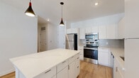 Located at 301 Ben Allen Rd in Nashville, TN, this well-designed one-bedroom, one-bathroom residence offers a clean, modern aesthetic across a comfortable single-floor layout. The open-concept kitchen and living area serves as the heart of the home, showcasing sleek white cabinetry that extends to the ceiling, a quartz-topped island with pendant lighting, and a full suite of stainless steel appliances including a refrigerator, electric range, and built-in microwave. A subtle tile backsplash adds texture to the kitchen's crisp, contemporary finish. Light-toned hardwood flooring flows seamlessly throughout the living spaces, enhancing the bright and airy atmosphere created by white walls and recessed lighting. The living area features French doors with blinds, inviting natural light and providing outdoor access. The bedroom is a comfortable retreat with a ceiling fan, natural light from a window with outdoor views, and ample closet space supported by two dedicated closets. The bathroom is finished with large-format tile flooring, a quartz vanity, framed mirror, and modern fixtures. A dedicated laundry area and hallway round out the functional layout, making this a well-appointed and efficient living space.