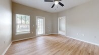 Located at 6200 Loyola Ln in Austin, TX, this single-story, 3-bedroom, 2-bathroom home offers a well-organized layout across a comfortably sized floor plan. The living room serves as the heart of the home, featuring warm wood-look laminate flooring, a ceiling fan, and a glass-paned exterior door that invites natural light and provides outdoor access. The kitchen runs adjacent to the living area and is outfitted with white cabinetry, light countertops, a built-in sink, and white appliances including a refrigerator and range. A utility room is conveniently accessible from the kitchen corridor. The three bedrooms are carpeted in neutral tones and each features ceiling fans. The primary bedroom includes a large window with outdoor views, while secondary bedrooms offer closet storage — one with a double-door closet. Both bathrooms feature wood-look vinyl flooring, white vanities with light countertops, and well-lit mirrors. The neutral, warm beige color palette used throughout the home creates a cohesive and inviting atmosphere. Two hallways connect the rooms efficiently, contributing to the home's functional flow. Overall, the space presents a clean, move-in-ready interior well-suited for comfortable everyday living.