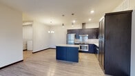 Located at 1128 Killdeer Ln SE in Rochester, MN, this thoughtfully designed residence offers a comfortable and functional single-floor layout with two bedrooms, one bathroom, and a dedicated closet. The open-concept kitchen serves as the centerpiece of the home, showcasing rich dark cabinetry, granite countertops, a central island with additional storage, and a full suite of stainless steel appliances including a refrigerator, range, dishwasher, and built-in microwave. Pendant lighting above the island and recessed ceiling lights enhance the kitchen's modern aesthetic. Light-toned hardwood-style flooring flows throughout the main living areas, lending a clean and cohesive look. The spacious living area benefits from a large picture window that fills the room with natural light and offers views of the surrounding neighborhood. Both bedrooms feature plush carpeting, individual windows with blinds, and neutral wall tones, providing a calm and restful atmosphere. The primary bedroom offers a comfortable footprint well-suited for a full furniture arrangement. The bathroom is finished with matching dark cabinetry, granite countertops, a large vanity mirror, and accessibility grab bars, combining practicality with consistent design. Overall, the residence presents a modern, move-in-ready interior with cohesive finishes throughout.