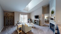 This thoughtfully designed single-floor residence offers an impressive blend of architectural character and functional living spaces. The living room serves as the heart of the home, boasting dramatic vaulted ceilings with a large skylight that floods the space with natural light, plush carpeting, a fireplace, and sliding glass doors that open to a private balcony overlooking lush outdoor scenery. An elegant arched niche adds a refined architectural detail to this central gathering area.

The dining area features vaulted ceilings accented by a classic chandelier, creating an intimate yet stylish setting for meals. The kitchen is well-equipped with white cabinetry, granite-toned countertops, a tile backsplash, and wood-style flooring, providing both practicality and charm.

The primary bedroom impresses with soaring ceilings, plush carpet, a walk-in closet, and a private en-suite bathroom complete with a vanity featuring dark countertops and a glass-enclosed shower. An additional bedroom showcases its own vaulted ceiling with a ceiling fan and a charming octagonal window, making it a versatile and inviting space.

A shared bathroom with white cabinetry and granite-style countertops serves the remaining rooms. Throughout, warm neutral tones, plush carpeting, and abundant natural light create a cohesive and welcoming ambiance.