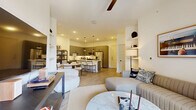 This well-appointed two-bedroom, four-bathroom single-story residence offers a thoughtfully designed open-concept layout with clean, modern finishes throughout. Light wood-tone flooring flows seamlessly across the main living areas, tying together the living room, dining area, and kitchen into one cohesive, social space. The living room is bright and inviting, featuring a ceiling fan, recessed lighting, and French doors that open to a private balcony with outdoor views. The kitchen is a standout feature, showcasing gray flat-front cabinetry, stainless steel appliances, a white quartz waterfall island with bar seating, and sleek pendant lighting — all designed for both function and style. Both bedrooms are well-proportioned and filled with natural light from large windows framed by floor-length curtains. The primary bedroom includes generous closet space with built-in shelving and hanging rods. The four bathrooms are finished with contemporary fixtures, including matte black hardware, clean-lined vanities, and tiled tub-shower combinations. Additional highlights include a dedicated laundry room, utility room, hallway, and four closets for abundant storage. The overall ambiance is modern, clean, and move-in ready.