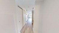 Located on the 9th floor of McPherson Square NE in Calgary, Alberta, this contemporary one-bedroom, one-bathroom unit offers a clean, modern aesthetic throughout. Light-toned hardwood-style flooring runs seamlessly across the entire space, complementing the crisp white walls and creating a bright, cohesive interior.

The open-concept kitchen and living area form the heart of the unit. The kitchen is outfitted with full-height white cabinetry, white quartz countertops, a classic subway tile backsplash, and a complete suite of stainless steel appliances including a range, over-the-range microwave, dishwasher, and refrigerator. Track lighting above provides ample task illumination. The adjacent living area is anchored by floor-to-ceiling windows that frame striking panoramic views of the Calgary skyline, filling the space with abundant natural light.

A hallway fitted with a large sliding-door closet connects the living area to the bedroom. The bedroom is a well-proportioned retreat featuring exposed concrete architectural columns that add an industrial character, white walls, and a clerestory window for additional natural light. The unit's minimalist design and neutral palette offer a versatile canvas, while the elevated city views make this a standout feature of the space.