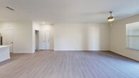 This single-story residence offers a thoughtfully designed layout encompassing 2 bedrooms, 3 bathrooms, and a seamlessly integrated kitchen and living area. The open-concept living space features light-toned luxury vinyl plank flooring, neutral walls, and recessed lighting, creating a bright and inviting atmosphere. The modern kitchen is equipped with stainless steel appliances, a spacious quartz-topped island with an undermount sink, white shaker upper cabinets, navy lower cabinets, subway tile backsplash, and stylish pendant lighting. Both bedrooms are carpeted and receive ample natural light through blinded windows, each outfitted with a ceiling fan. The primary bedroom includes access to a dedicated walk-in closet featuring built-in shelving and hanging rods for generous storage. The bathrooms are finished with clean white quartz countertops, undermount sinks, and navy cabinetry accented by brushed nickel hardware. A private balcony extends the living space outdoors, enclosed by sleek black metal railings and offering pleasant views of the surrounding landscaping and community. A hallway connects the rooms efficiently, completing this well-organized and contemporary single-floor home.