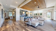 Located at 400 Hidden Palm Cir in Kissimmee, Florida, this single-story community clubhouse offers a generously sized, thoughtfully designed gathering space with a warm coastal-contemporary aesthetic. The main lounge anchors the layout with soaring wood-planked ceilings, exposed beams, wide-plank hardwood flooring, and large glass doors that open directly to the outdoor pool area, flooding the interior with natural light and views of the surrounding community.

The open-plan social area flows seamlessly into a kitchenette and bar zone, where quartz countertops, shaker-style cabinetry, a matte black faucet, and a decorative tile backsplash create an elegant yet functional serving station. Patterned cement tiles define the bar area, adding visual contrast to the wood floors.

A dedicated game room features a full-size billiards table, wall-mounted television, high-top bar seating, and statement brass pendant lighting, alongside a separate room equipped with an arcade machine for casual entertainment. A card and games room with a round poker table and soft neutral carpeting provides a quieter retreat.

The dining area offers comfortable banquette-style booth seating with striped upholstery and elegant pendant chandeliers, ideal for group gatherings. Throughout, shiplap wall detailing, ceiling fans, and recessed lighting tie the space together with a refined, resort-inspired character.