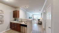 Located at 536 Tenby Dr in Rock Hill, SC, this well-appointed 2-bedroom, 2-bathroom home presents a thoughtfully designed single-floor layout that maximizes comfort and functionality. The open living room is bright and welcoming, featuring light wood-look flooring, crown molding, and large windows that invite natural light and outdoor views. A peninsula kitchen with rich dark wood cabinetry, light granite-style countertops, a stainless steel sink, and black appliances flows seamlessly from the living area, with a breakfast bar providing convenient seating for two. The primary bedroom is generously sized, offering plush carpet, a ceiling fan, and a dedicated closet. The second bedroom also features carpet flooring, a ceiling fan, natural light from a window with outdoor views, and its own closet. Both bathrooms are consistently finished with warm wood vanities, light countertops, large mirrors with vanity lighting, and shower/tub combos set on light wood-look flooring. A hallway connects the main living spaces to the bedrooms and bathrooms, ensuring a practical and cohesive layout throughout. The overall aesthetic is clean and neutral, with warm tones and consistent finishes that create an inviting, move-in-ready atmosphere.