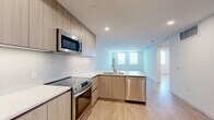 This modern 1-bedroom, 1-bathroom unit in San Diego, CA (92103) offers a well-designed, single-level layout with contemporary finishes throughout. Light wood-tone flooring runs continuously across the space, complementing the clean white walls and creating a bright, cohesive aesthetic.

The open-concept kitchen is a standout feature, outfitted with flat-front wood-grain cabinetry, white quartz countertops, and a full suite of stainless steel appliances including a French door refrigerator, electric range, over-the-range microwave, and dishwasher. A peninsula with an integrated sink and additional counter space connects the kitchen to the living area, making it ideal for both cooking and entertaining.

The bedroom is generously proportioned with large windows that invite natural light and offer views of the surrounding San Diego cityscape. A dedicated walk-in closet with built-in shelving and hanging rods provides ample storage.

The bathroom features a soaking tub with full-height marble-style tile surround, wood-grain vanity with a white undermount sink, and recessed lighting, delivering a clean, spa-inspired feel. Recessed lighting throughout the unit enhances the modern design, while the overall neutral palette ensures a versatile and welcoming atmosphere.