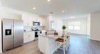 Located on Peaceful Brook Loop in Punta Gorda, Florida, this single-story home offers four bedrooms and three bathrooms within a well-organized, functional floor plan. Wood-look luxury vinyl flooring runs continuously throughout the home, lending a cohesive and clean aesthetic from room to room.

The open-concept kitchen and living area serves as the heart of the home. The kitchen features crisp white cabinetry, granite countertops, a stainless steel appliance suite including a refrigerator, range, and microwave, and a central island with bar seating — ideal for casual dining or entertaining. Recessed lighting illuminates the space, which flows naturally into the adjoining living area brightened by multiple windows.

Wide hallways connect the bedrooms, maintaining an open and airy feel throughout. The spacious primary bedroom includes a dedicated walk-in closet with wire shelving and a private en-suite bathroom with a granite-topped vanity and walk-in shower. Additional bedrooms are well-proportioned, each featuring ceiling fans and natural light. The bathrooms maintain a consistent, clean design with white finishes.

A dedicated laundry area with a full-size washer and dryer adds everyday convenience, completing this thoughtfully designed Florida home.