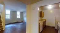 This two-floor space offers a straightforward and functional layout designed for comfortable everyday living. The main level features a semi-open floor plan where the kitchen and living area are connected yet defined by a structural dividing wall, creating a sense of organization while maintaining an open feel.

The kitchen is equipped with warm wood-toned cabinetry, a double-basin sink, a dishwasher, and a continuous countertop that provides ample workspace. The cabinetry offers generous storage with both upper and lower cabinets, making the kitchen practical and efficient.

Adjacent to the kitchen, the living area is characterized by rich, dark hardwood flooring that extends throughout the space, adding warmth and a classic aesthetic. A window allows natural light to filter in, brightening the room and creating an inviting atmosphere. A baseboard heating system runs along the perimeter, ensuring year-round comfort.

The cream-colored walls and clean lines throughout the space contribute to a neutral, versatile interior that can be easily personalized. The overall ambiance is understated and functional, with durable finishes and a layout that maximizes the use of available space across both floors.