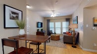 Located at 830 Fasken Blvd in Laredo, Texas, this single-floor residence offers a thoughtfully designed layout with a seamless flow between living, dining, and kitchen areas. The living room is a welcoming, light-filled space featuring large windows with blinds and grommet-panel curtains, a ceiling fan, light hardwood-style flooring, and a wall-mounted flat-screen TV above a wood-and-metal media console. The open kitchen is outfitted with rich dark wood cabinetry, a full suite of white appliances including a range, microwave, dishwasher, and refrigerator, plus tile flooring and ample counter space. A dining area with a wood bar-height table connects the kitchen and living spaces naturally. A hallway leads to the bedroom, which features plush carpet, a walk-in closet with built-in shelving, a ceiling fan, and direct access to a private exterior door. The bedroom's warm, neutral palette creates a calm, restful atmosphere. The bathroom is clean and functional, with tile flooring, a tub-shower combination, and dark wood cabinetry. A separate flex room with carpet, natural light, and its own exterior door serves well as a home office or secondary space. Neutral warm-beige walls and consistent finishes tie the entire residence together.